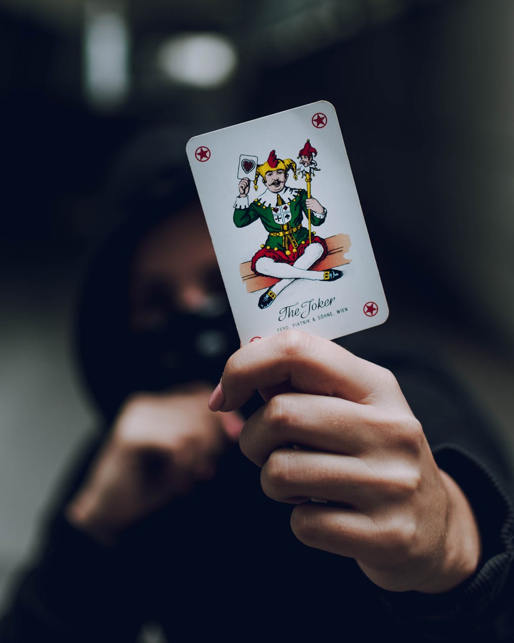 selective focus photo of person holding joker playing card